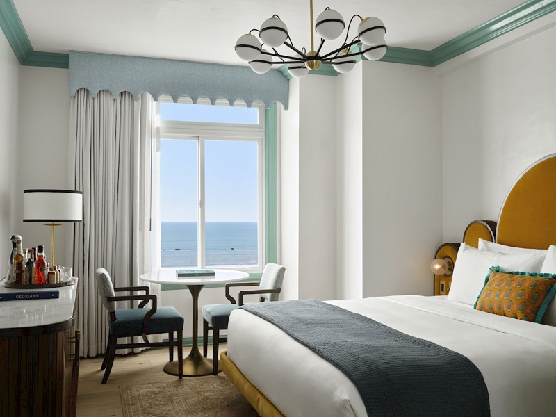 A guest room at The Georgian hotel: seafoam Art Deco cornice, scalloped valance, and the Pacific through the window.